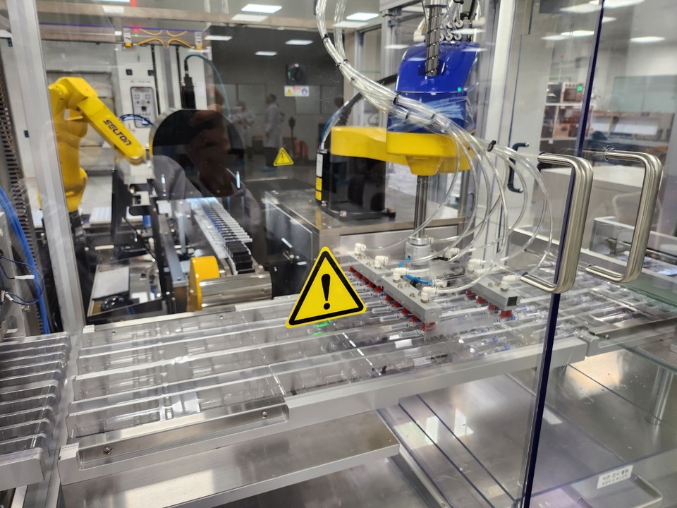 노란색 로봇팔이 '스카이셀플루' 프리필드 시린지들을 블리스터 포장재 내로 옮기고 있다. / 사진=박성수 기자