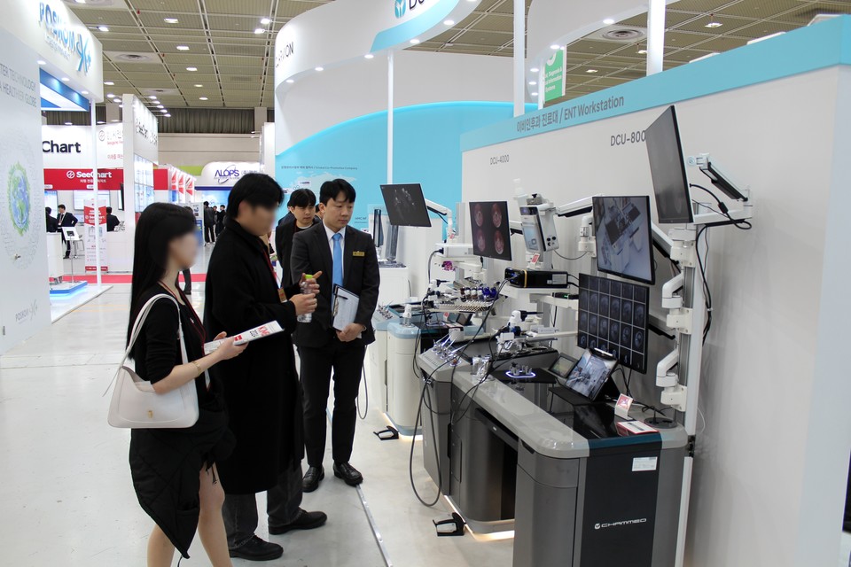 KIMES 2024에서 동아참메드 직원이 동아참메드 부스에 방문한 고객사 직원에게 이비인후과 진료대 DCU-8000에 대해 설명하고 있다. / 사진=동아참메드