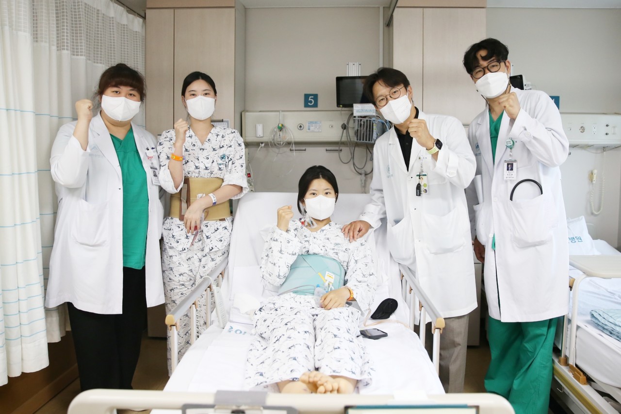 다낭성 신증후군으로 만성 신부전을 앓던 이가영 씨(가운데)가 로봇 신장이식 후 지난 20일 의료진과 기념사진을 찍고 있다. (왼쪽에서 두 번째)공여자인 언니 이 모 씨, (왼쪽에서 네 번째) 수술을 집도한 서울아산병원 신ㆍ췌장이식외과 신성 교수.