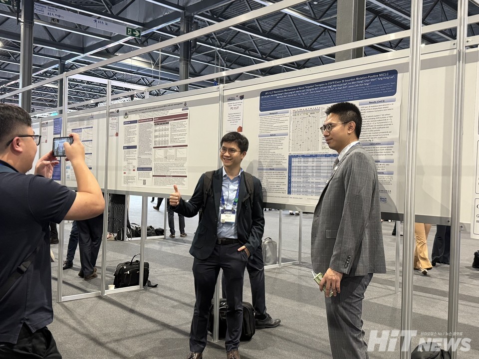 루타테라 포스터 앞에서 기념사진을 촬영하는 사람들