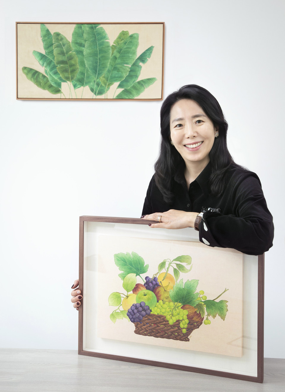 6년째 모던민화를 그리고 있는 전은정 피알봄 대표가 가장 최근작인 '과일 바구니'(2025)를 들고 있다. 그의 뒤로 마음 수양과 내면의 힘을 상징하는 작품 '파초'(2021)도 보인다.