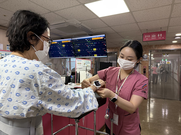 간호사가 환자에게 스마트 병상 모니터링 시스템 씽크와 연동되는 웨어러블 기기를 착용시키고 있다. 사진=대웅제약 제공.
